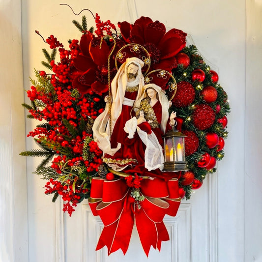 mary and jesus christmas wreath with pre lit lantern and red bow and beery and red ornaments 